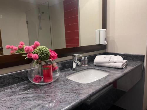 a bathroom sink with pink flowers in a vase at Marbella Hotel in Jounieh