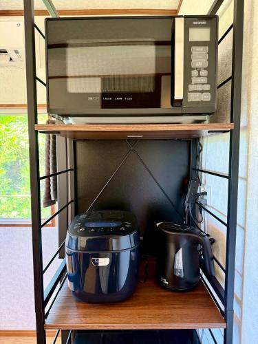 a microwave and a slow cooker on a shelf at 鴨川シーサイドヴィラ in Kamogawa