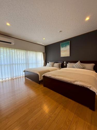 a bedroom with two beds and a large window at 鴨川シーサイドヴィラ in Kamogawa
