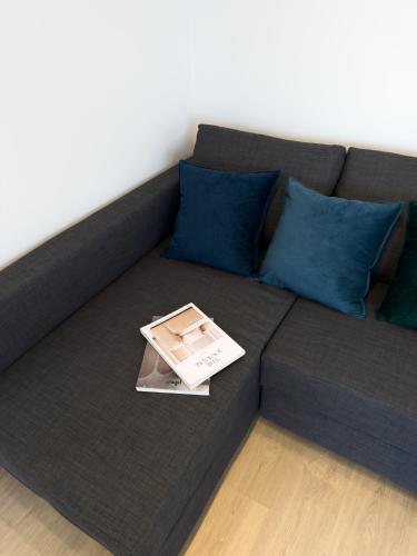 a couch with blue pillows and a book on it at 107 - Beachside Renovated 1BR apt 5 min from Beach in Cambrils
