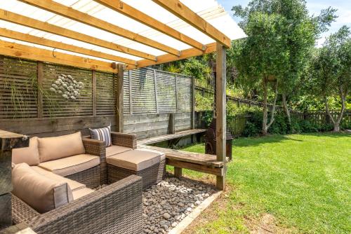 eine Terrasse mit einer Bank und einer Pergola in der Unterkunft Bach 22 at Palm Beach in Waiheke Island