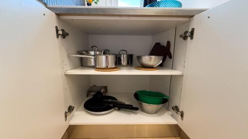 a cupboard with some pots and pans in it at 103 - Beachside Renovated 1BR apt w private garden in Cambrils