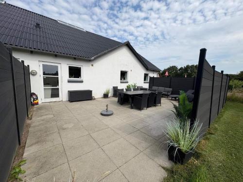 a patio with black furniture and a white house at 4 star holiday home in Henne in Henne