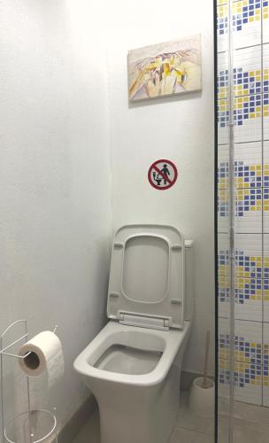 a bathroom with a toilet with a sign on the wall at Ho&En - Coastal Serenity Entire Rental Unit in Durrës, Albania in Durrës