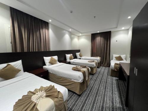 a hotel room with three beds and two tables at فندق اسفار الحجاز 2 in Al Masfalah