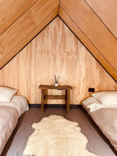 a room with two beds and a table in a tent at Parque Laguna de Zapallar in Maitencillo