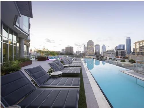 a row of lounge chairs next to a pool on a building at Spacious Luxury 1bedroom 1bath Pool in Austin