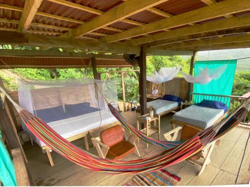 a hammock in a room with a bed and a bed at Casinha da Floresta in Santa Marta