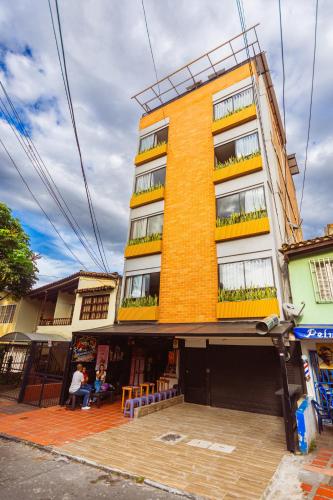 a tall yellow building with balconies on a street at Comuna Loft in Medellín