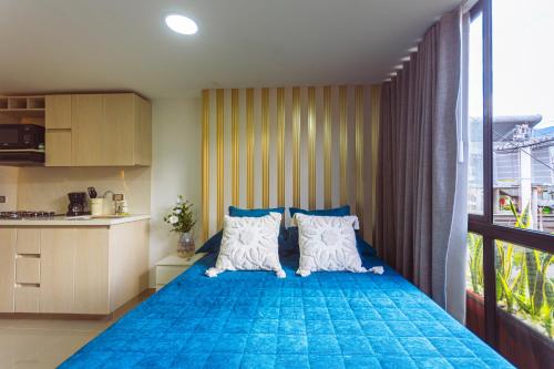 a bedroom with a blue bed with a large window at Comuna Loft in Medellín