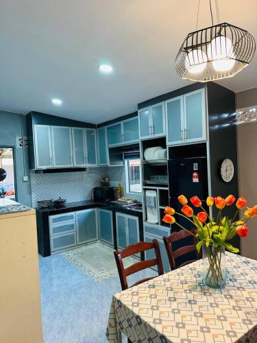 a kitchen with blue cabinets and a table with orange flowers at Zalena's Homestay in Kuala Kerai