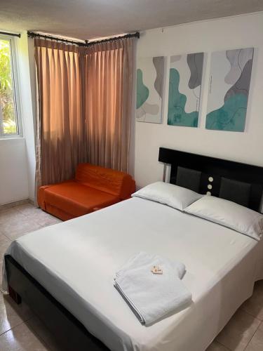 a bedroom with a large white bed and a chair at Casa Hostal Rico Vacile in Valledupar