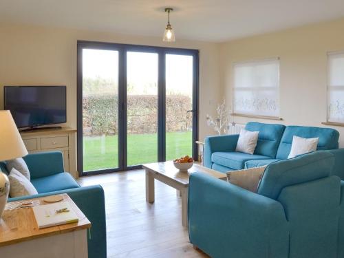a living room with blue couches and a tv at Robin Cottage - Ukc3436 in Newton Abbot