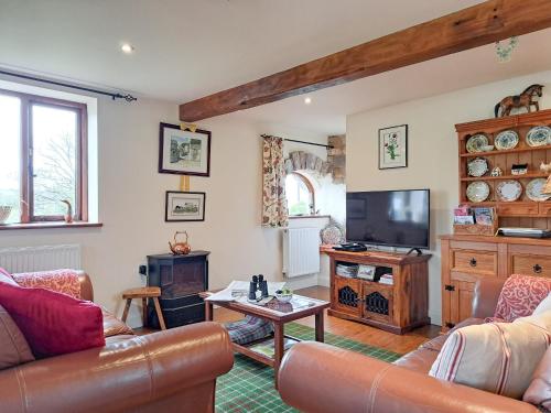 ein Wohnzimmer mit Sofa und Fernseher in der Unterkunft Bryn Dedwydd Cottage in Llanferres