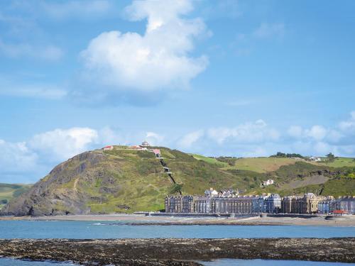 a building on a hill next to the water at Glennydd in Bronant
