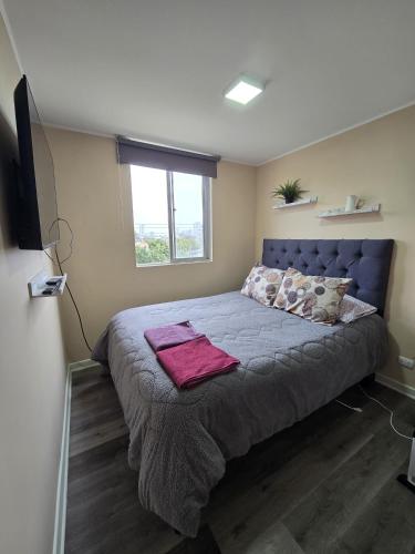 a bedroom with a bed with a blue headboard and a window at Espacio moderno y acogedor departamento en Rancagua in Rancagua