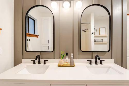 a bathroom with two sinks and two mirrors at Sleeps 10 Cozy Modern Cabin- 5 minutes to lake, fishing, & hiking in Crestline
