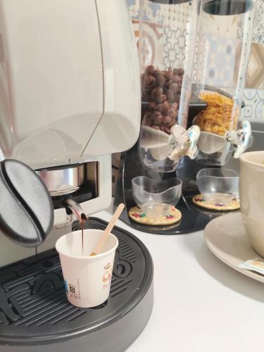 una macchina per il caffè con una tazza su un fornello di B&B Alle porte del centro a Santa Maria Capua Vetere