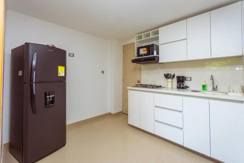 a kitchen with a black refrigerator and white cabinets at Comuna Loft in Medellín