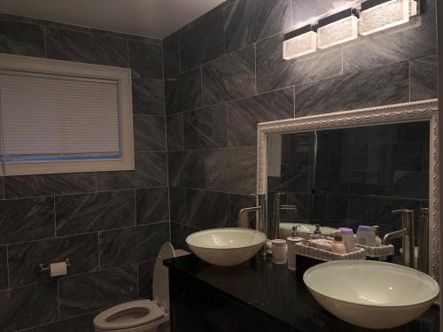 a bathroom with two sinks and a toilet and a mirror at Cheerful 3-bedroom home in Newnan