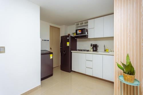 a kitchen with a black refrigerator and white cabinets at Comuna Loft in Medellín