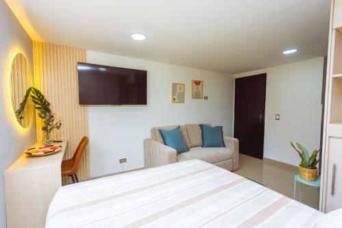a bedroom with a bed and a couch and a tv at Comuna Loft in Medellín