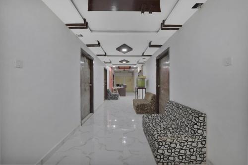 a hallway with chairs in a building with white walls at Hotel O Rudra Palace in Ahmedabad