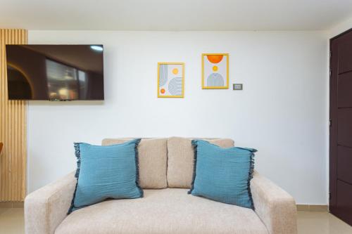 a couch with two blue pillows in a living room at Comuna Loft in Medellín