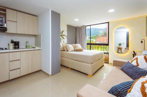 a bedroom with a bed and a couch and a kitchen at Comuna Loft in Medellín