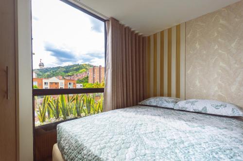 a bedroom with a bed and a large window at Comuna Loft in Medellín