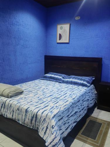 Un dormitorio azul con una cama con una pared azul. en YAIZA HOUSE Jaco, en Jacó