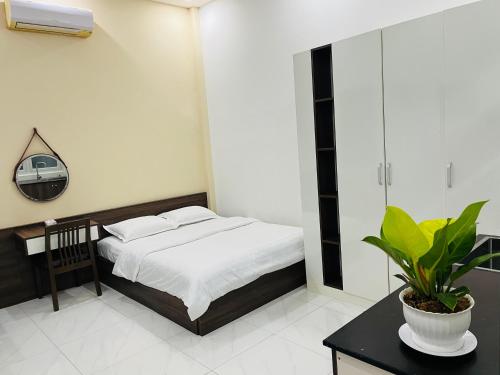 a bedroom with a bed and a table with a plant at AHK Homestay 1 in Phu Quoc