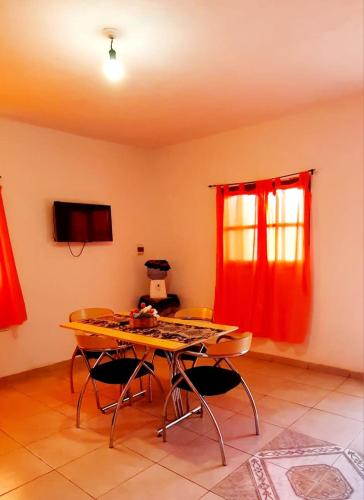 una mesa y sillas en una habitación con cortinas rojas en Mis Pichoncitos, en Villa Unión