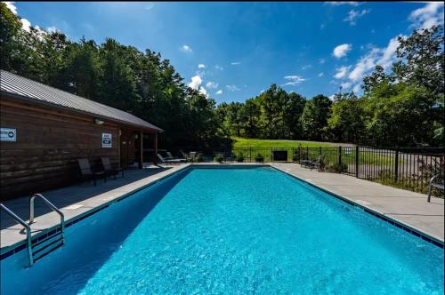 a swimming pool with blue water in front of a house at WOW, that View! NEW Luxury Cabin - Hot Tub - Pool Access - Game Room in Sevierville