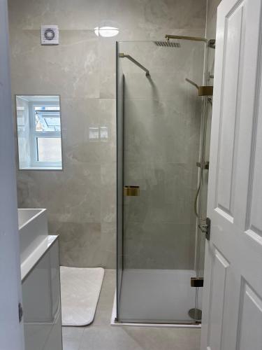 a shower with a glass door in a bathroom at The Beige House in Batley