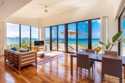 a living room with a dining table and a view of the ocean at アイネスヴィラノッツェ沖縄 in Nago