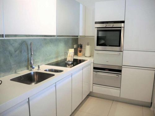 a white kitchen with a sink and a microwave at Residence Golf Parco in Ascona