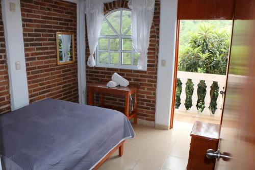 a bedroom with a bed and a brick wall at Hospedaje Migue y Cata y Centro Holístico Kuatlicue in Chignahuapan