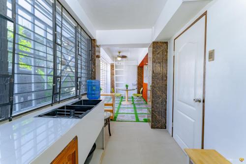 a kitchen with white counters and windows and a hallway at Ideal place to stay for 8-12pax with Parking Area in Mactan Island