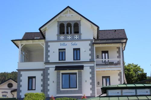 un gran edificio blanco con las palabras de venta de pueblo en él en Seeappartements Villa Sole en Pörtschach am Wörthersee