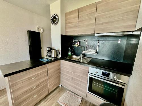 une cuisine avec des armoires en bois, un évier et une cuisinière dans l'établissement Appartement pour 4 face à la mer avec parking privé, à Sète - FR-1-338-619, à Sète