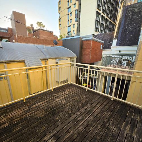 a balcony with a wooden deck with a yellow railing at The Regent Guesthouse in Sydney