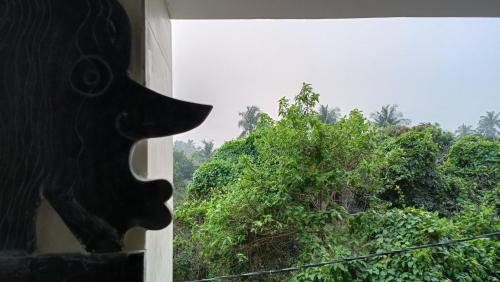 a dog looking out a window at a tree at NIRMAN HOMESTAY 5 minutes walk to beach in Puri
