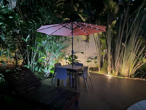 a table and chairs with an umbrella in a garden at Studio Apartment 2 & AC-2 Pools-Jungle-Beach-WiFi-TV in Cocles