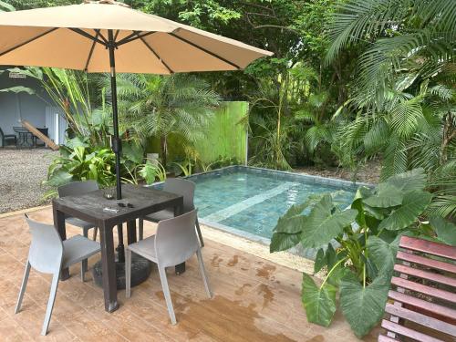 a table with an umbrella next to a swimming pool at Studio Apartment 2 & AC-2 Pools-Jungle-Beach-WiFi-TV in Cocles