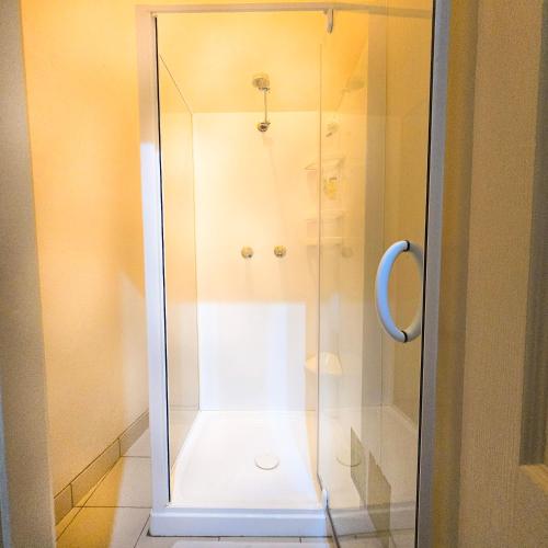 una ducha con puerta de cristal en un baño en The Regent Guesthouse, en Sídney