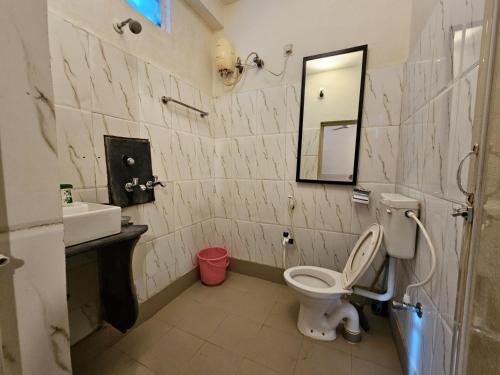 a bathroom with a toilet and a sink and a mirror at NIRMAN HOMESTAY 5 minutes walk to beach in Puri