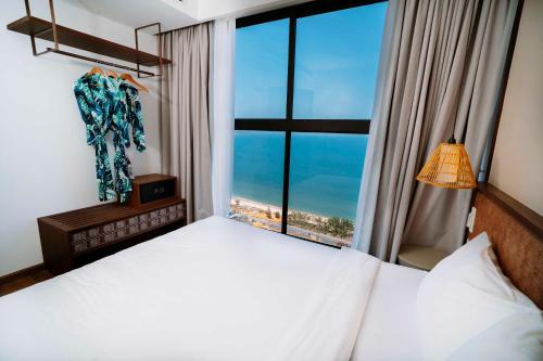 a bedroom with a bed and a large window at TT Luxury Condotel - Apec Mandala Mui Ne in Mui Ne
