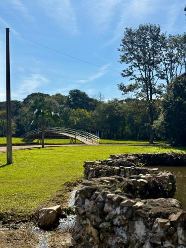 eine Brücke in einem Park mit einer Steinmauer in der Unterkunft Chácara Cidade da Divina Misericórdia in Araucária