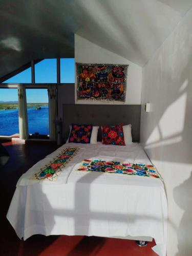 a bedroom with a white bed with pillows on it at Sumac wasi lodge uros in Puno
